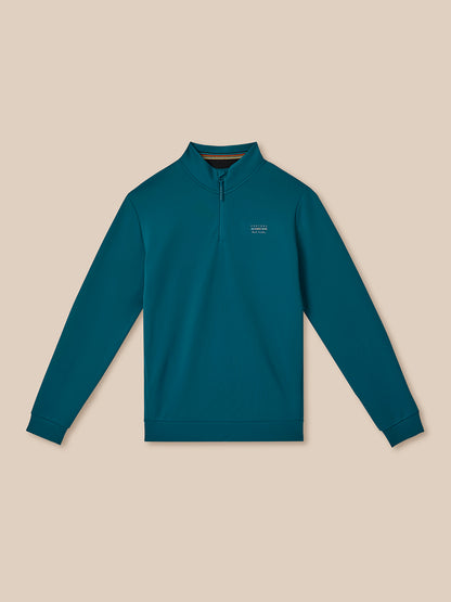 Teal long-sleeve shirt with a small logo on a beige background