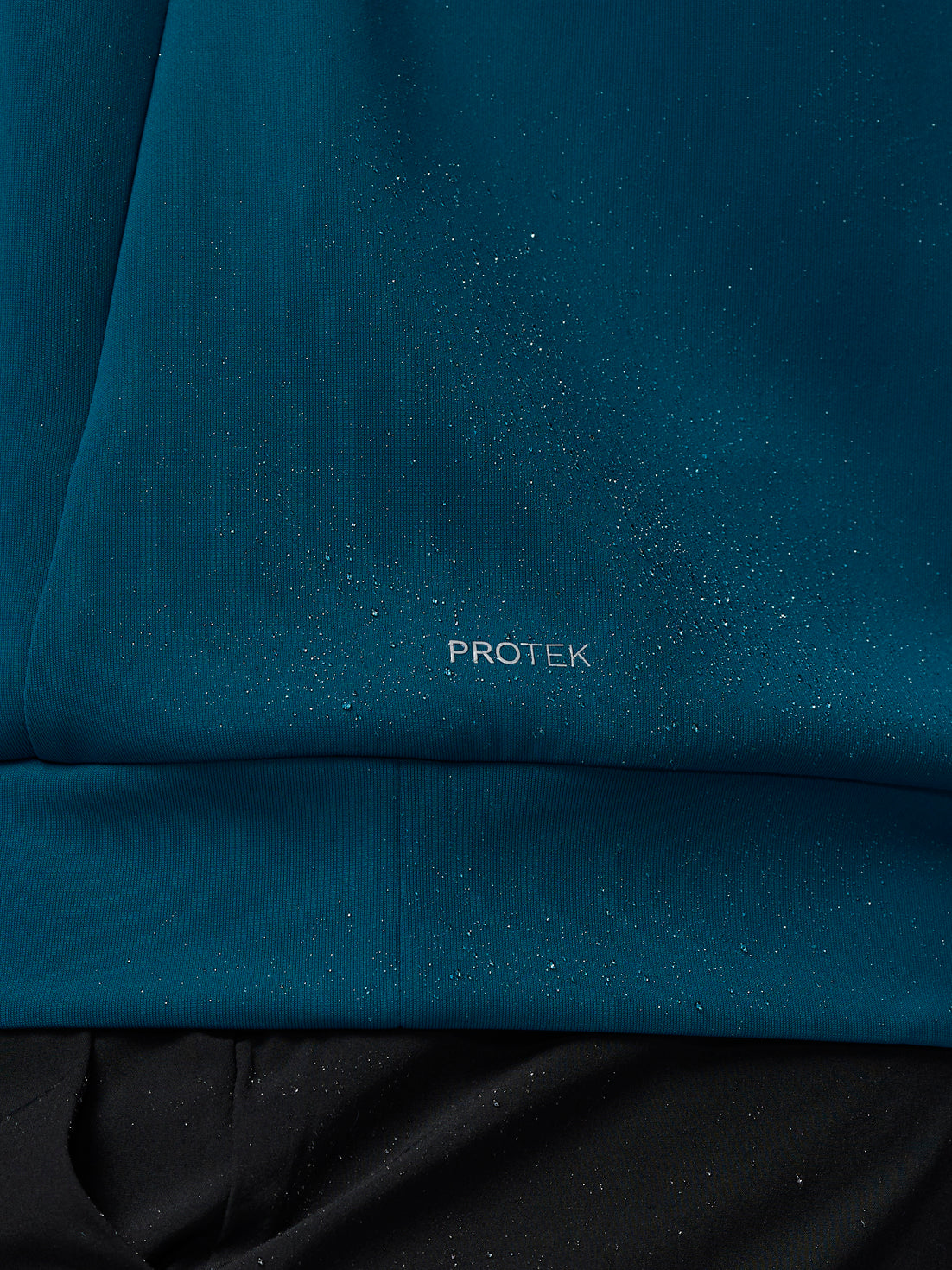 Close-up of blue fabric with 'PROTEK' branding.
