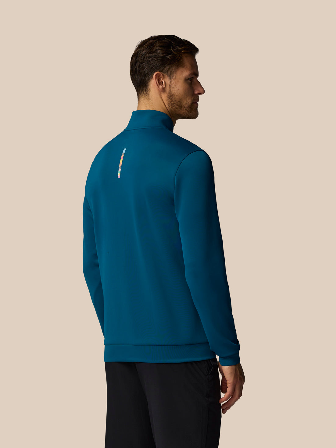 Man wearing a blue pullover with a zipper on a beige background