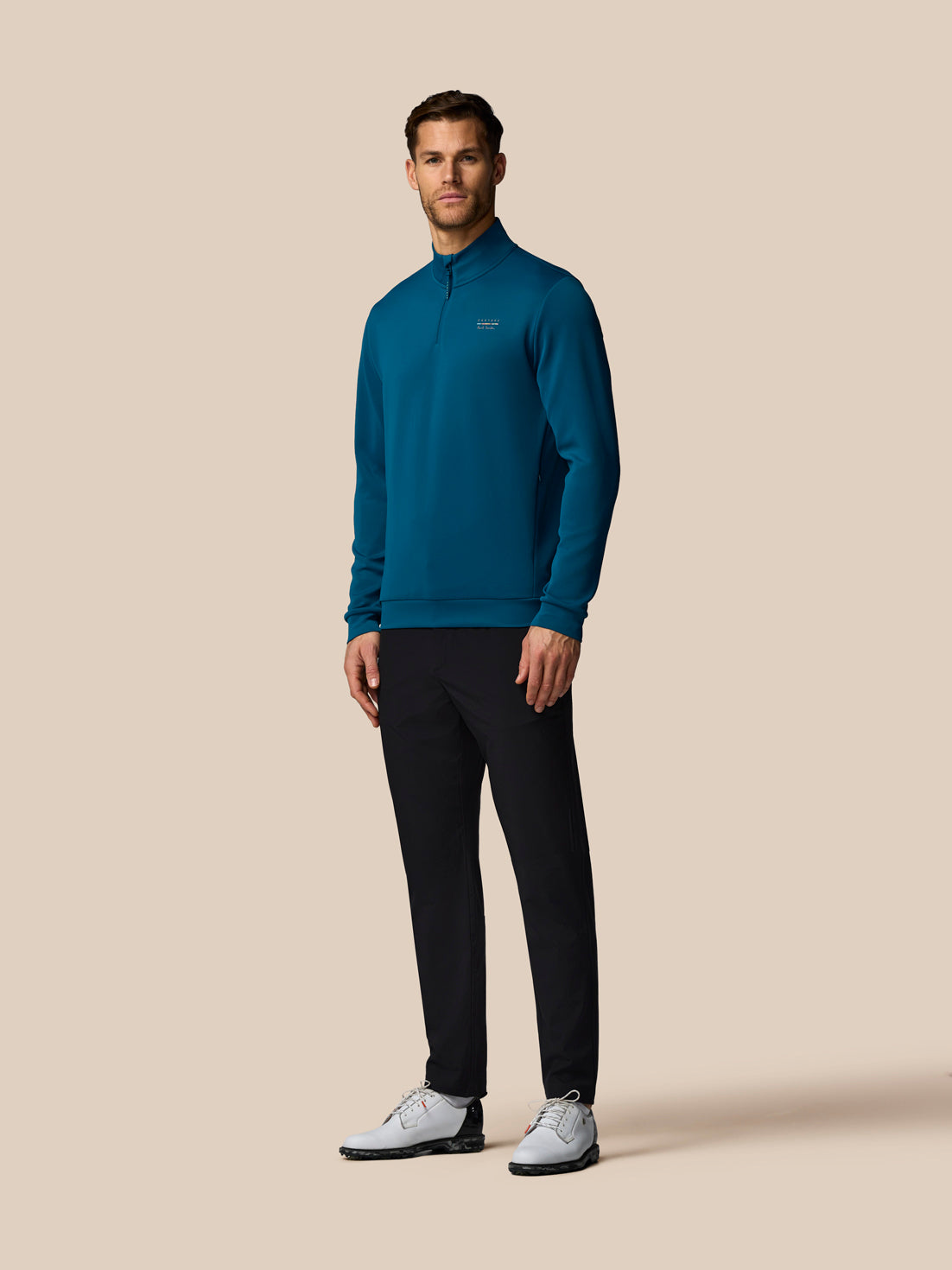 Man wearing a blue pullover and black pants on a beige background