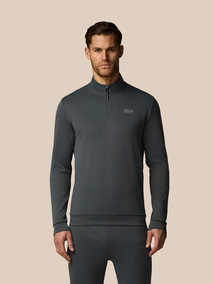 Man wearing a dark gray quarter-zip pullover with a visible brand logo on a beige background