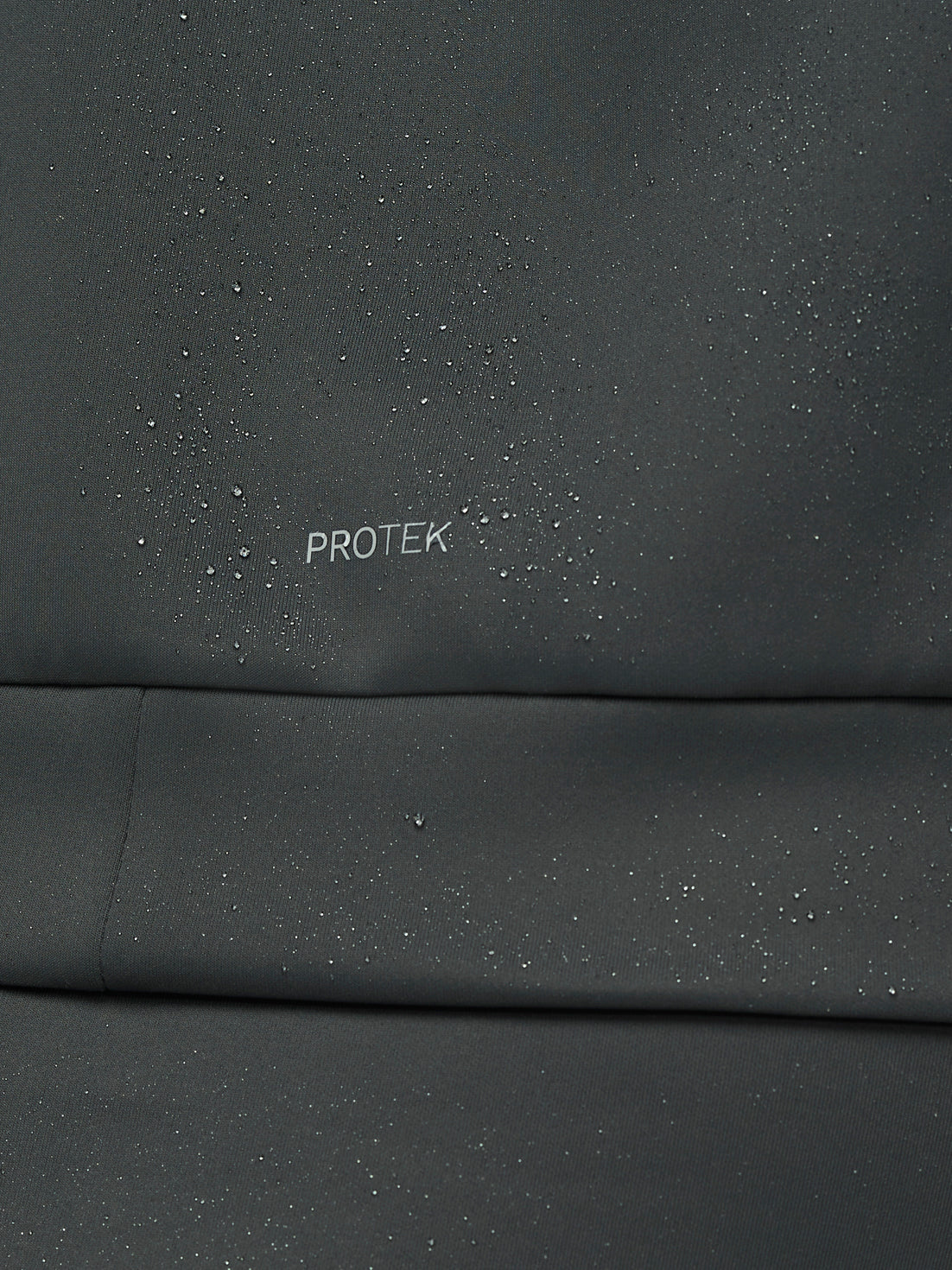 Dark gray fabric with 'PROTEK' branding on a close-up view