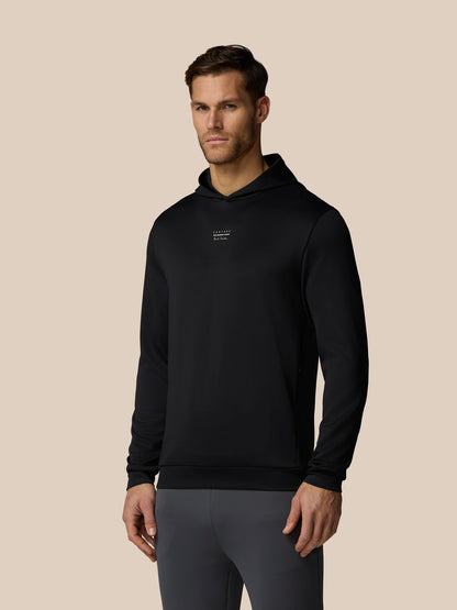Man wearing a black hoodie with a logo on a beige background