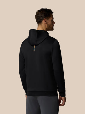 Man wearing a black hoodie from behind on a beige background