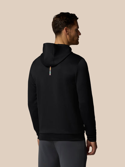Man wearing a black hoodie from behind on a beige background