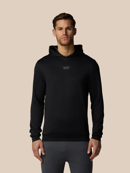 Man wearing a black hoodie with a logo on a beige background