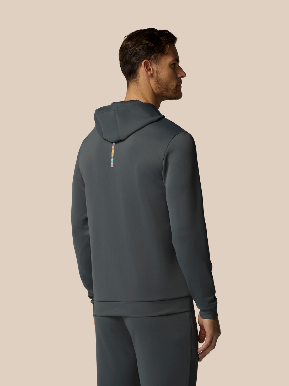 Man wearing a gray hoodie and pants on a beige background