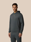 Man wearing a dark gray hoodie and pants on a beige background