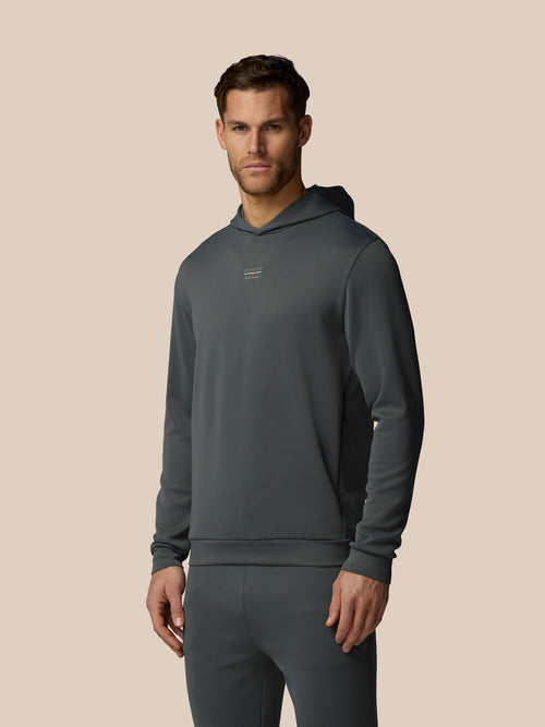Man wearing a dark gray hoodie and pants on a beige background