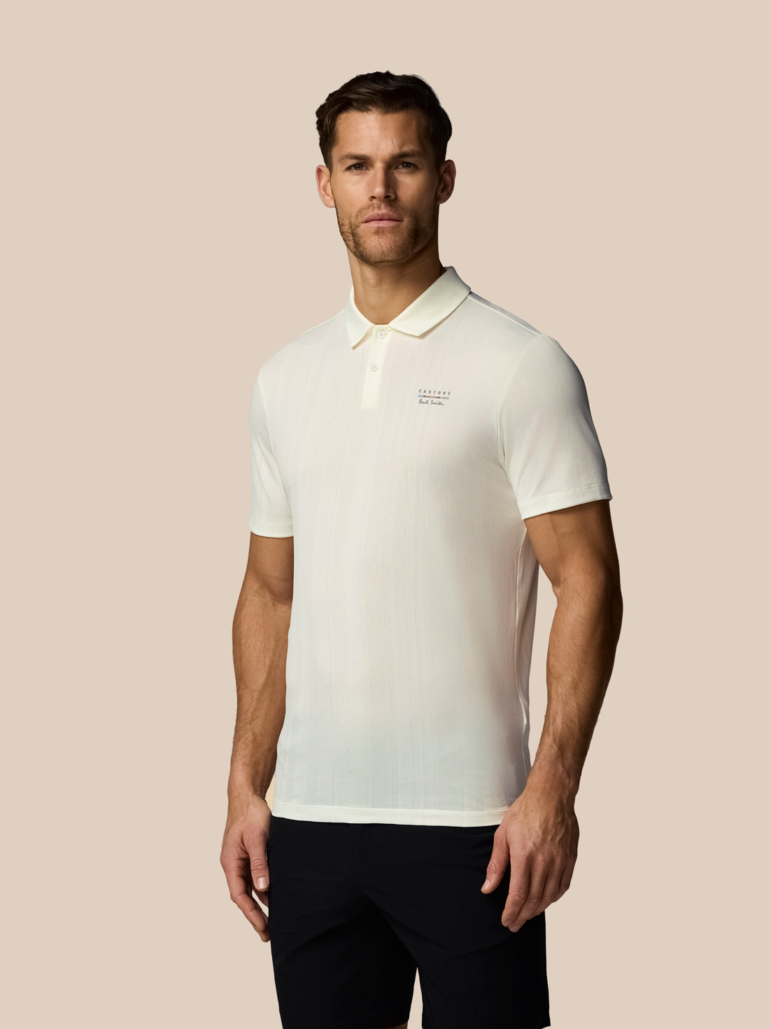 Man wearing a white polo shirt with a logo on a beige background