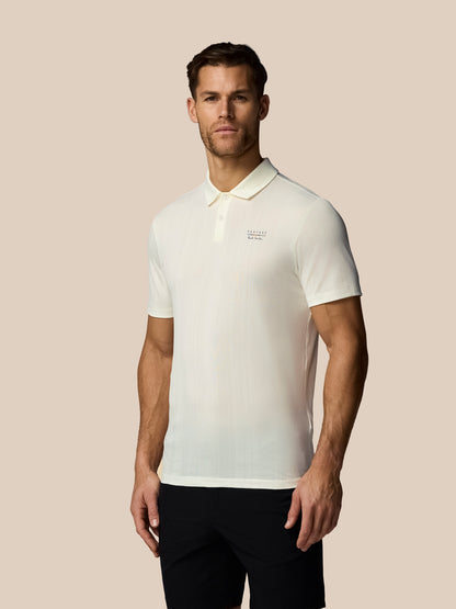 Man wearing a white polo shirt with a logo on a beige background
