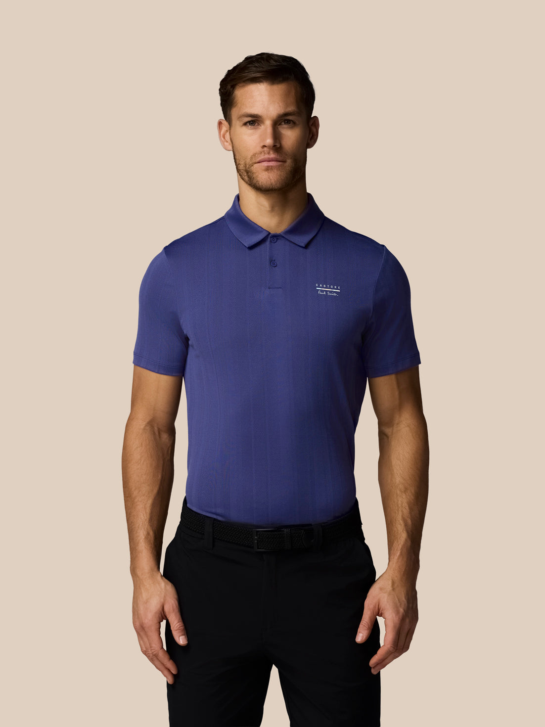 Man wearing a blue polo shirt with a logo on a beige background