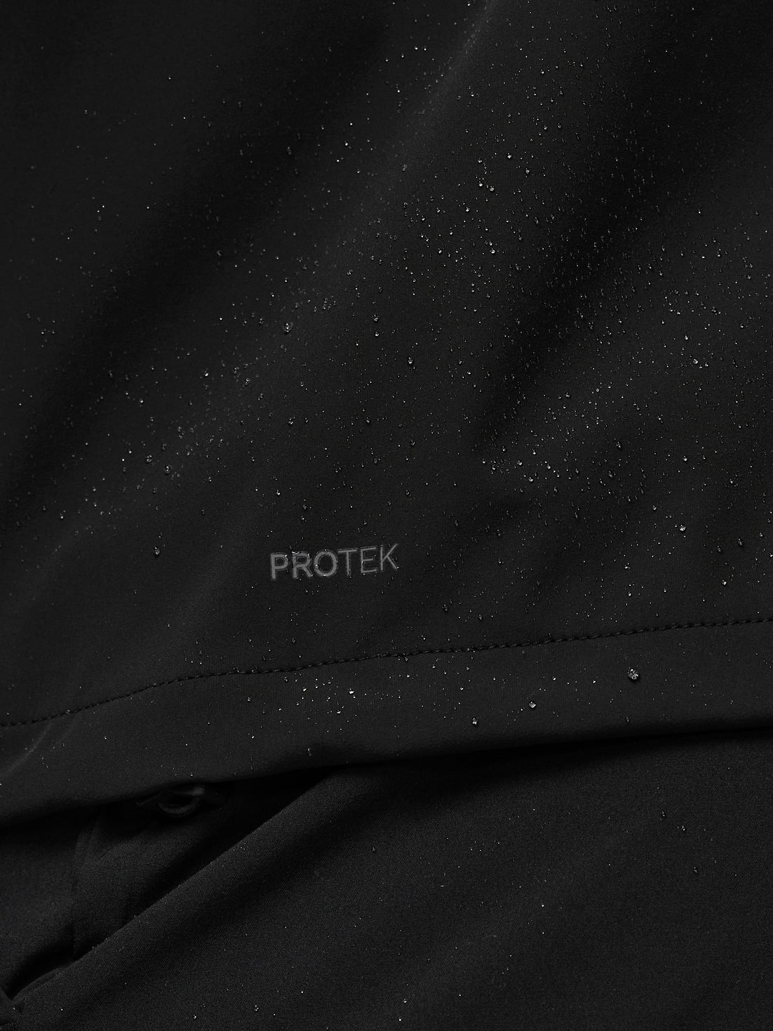 Close-up of black fabric with 'PROTEK' branding.