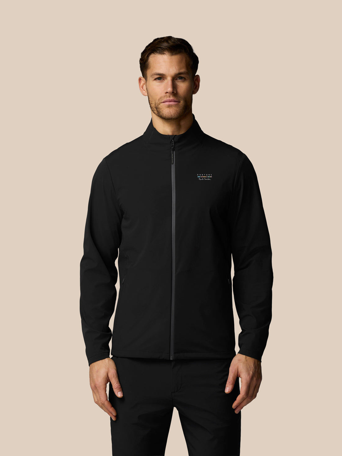 Man wearing a black jacket with a brand logo on a beige background
