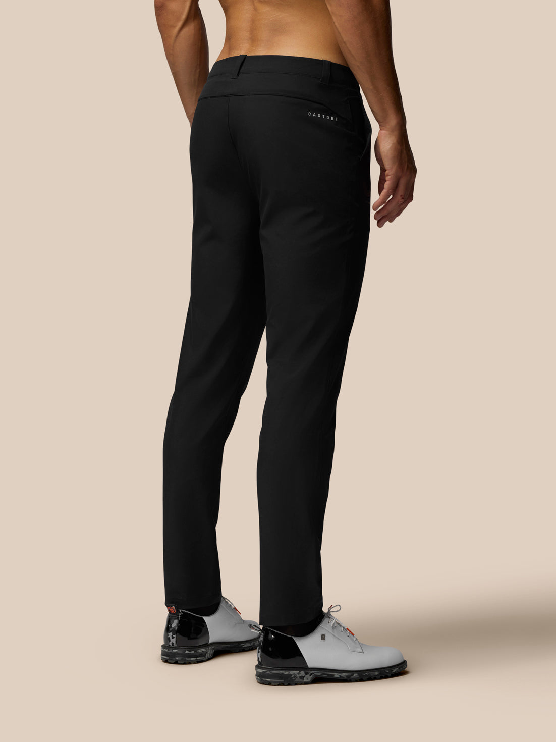 Back view of a man in black golf trousers with Castore branding on the back pocket.