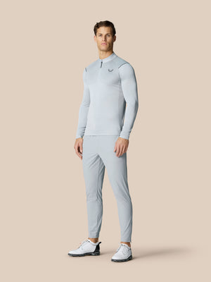 Male model wearing Golf Pinnacle Trousers 32 inch leg in mid grey against a beige backdrop.