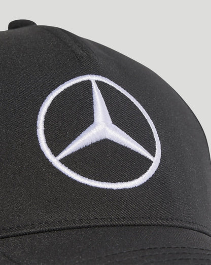 Close-up of black cap showing white embroidered Mercedes logo on the front