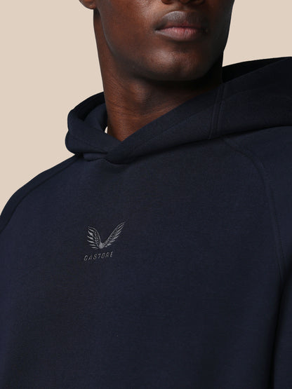Navy hoodie with a logo on the chest against a beige background