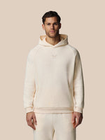 Man wearing a cream-colored hoodie and pants against a beige background