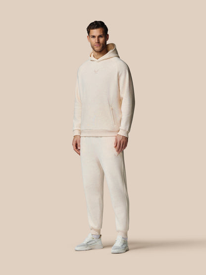 Man wearing a white hoodie and pants on a beige background