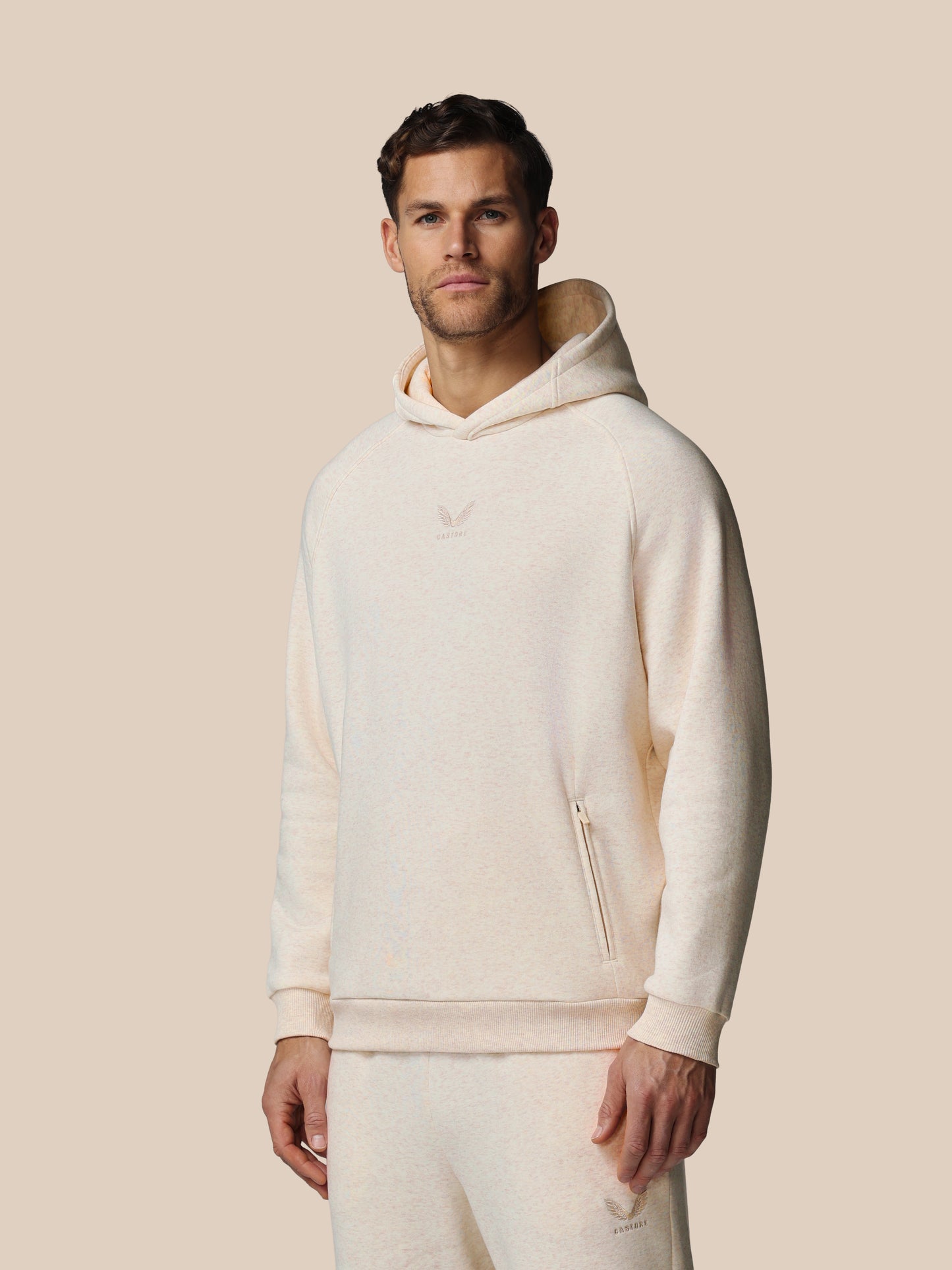 Man wearing a cream-colored hoodie against a beige background