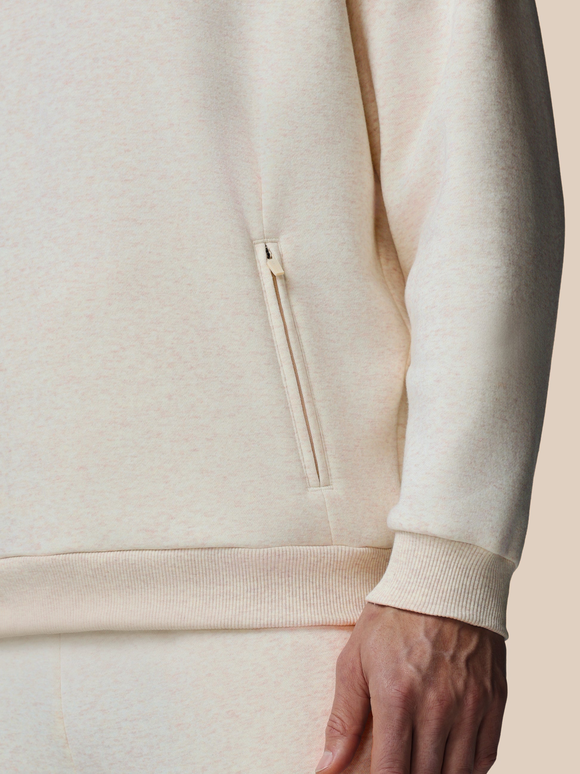 Close-up of a beige hoodie with a zipper on a neutral background