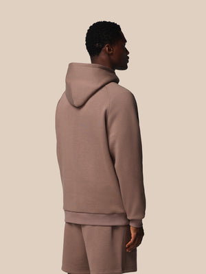 Person wearing a beige hoodie and shorts set on a plain background