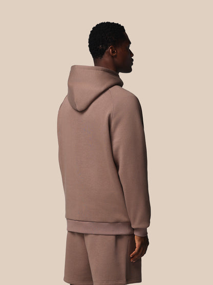 Person wearing a beige hoodie and shorts set on a plain background