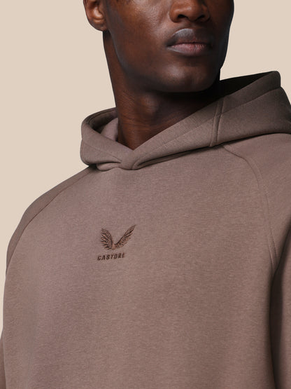 Brown hoodie with a logo on the chest against a beige background