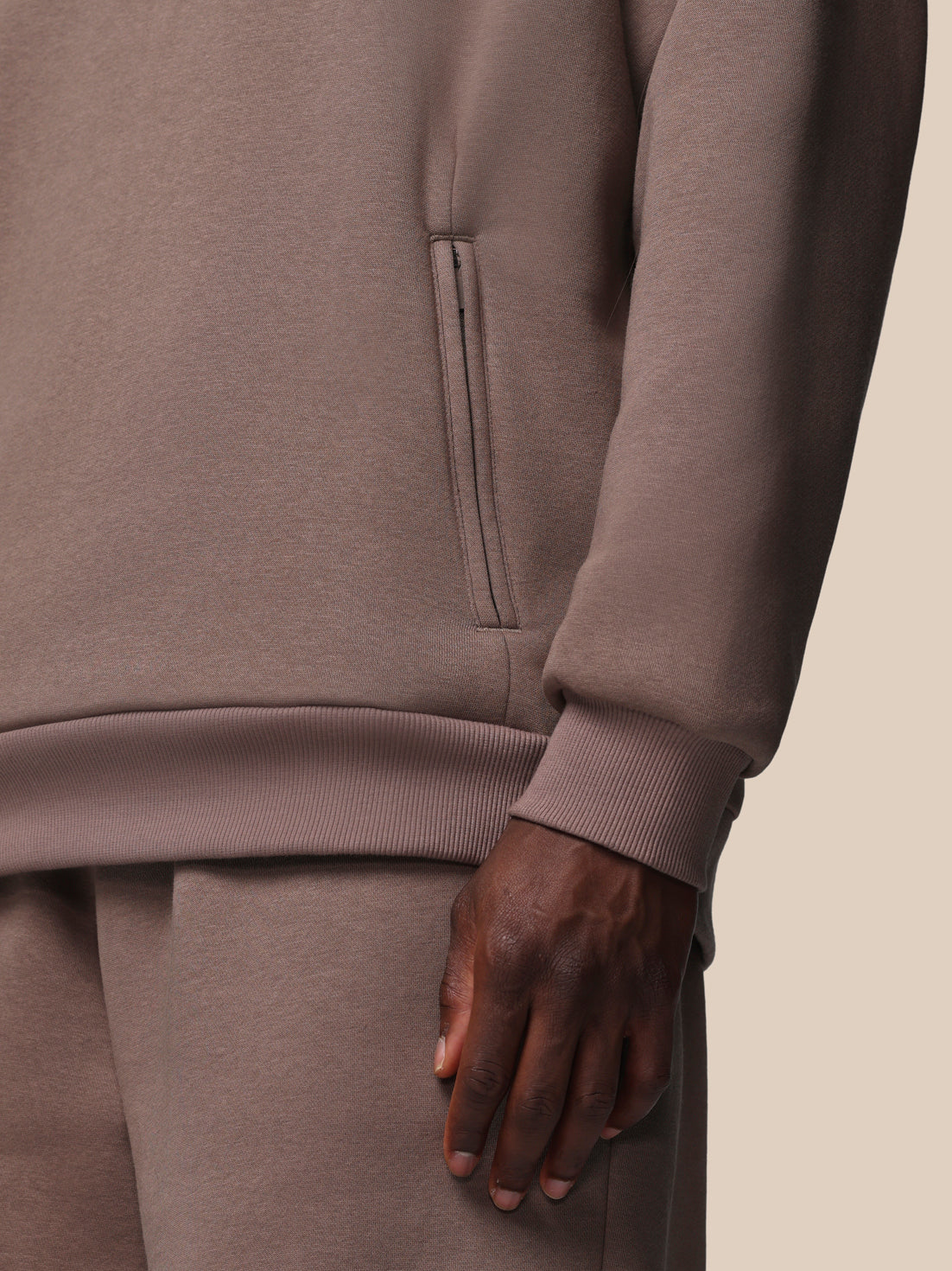 Close-up of a person wearing a brown tracksuit with a neutral background