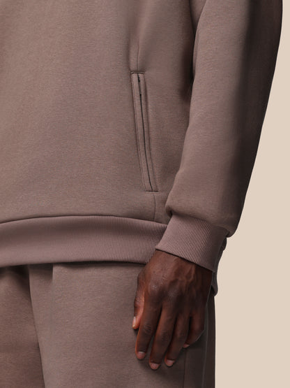 Close-up of a person wearing a brown tracksuit with a neutral background
