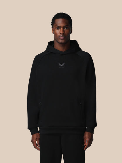 Man wearing a black hoodie with a logo on a beige background