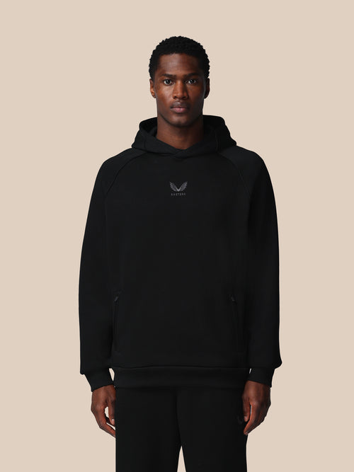 Man wearing a black hoodie with a logo on a beige background