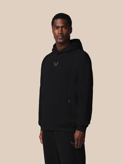 Person wearing a black hoodie with a logo on a beige background