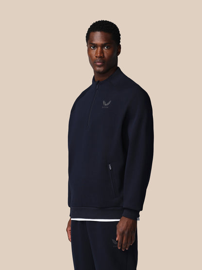 Man wearing a dark blue pullover with a logo on a beige background