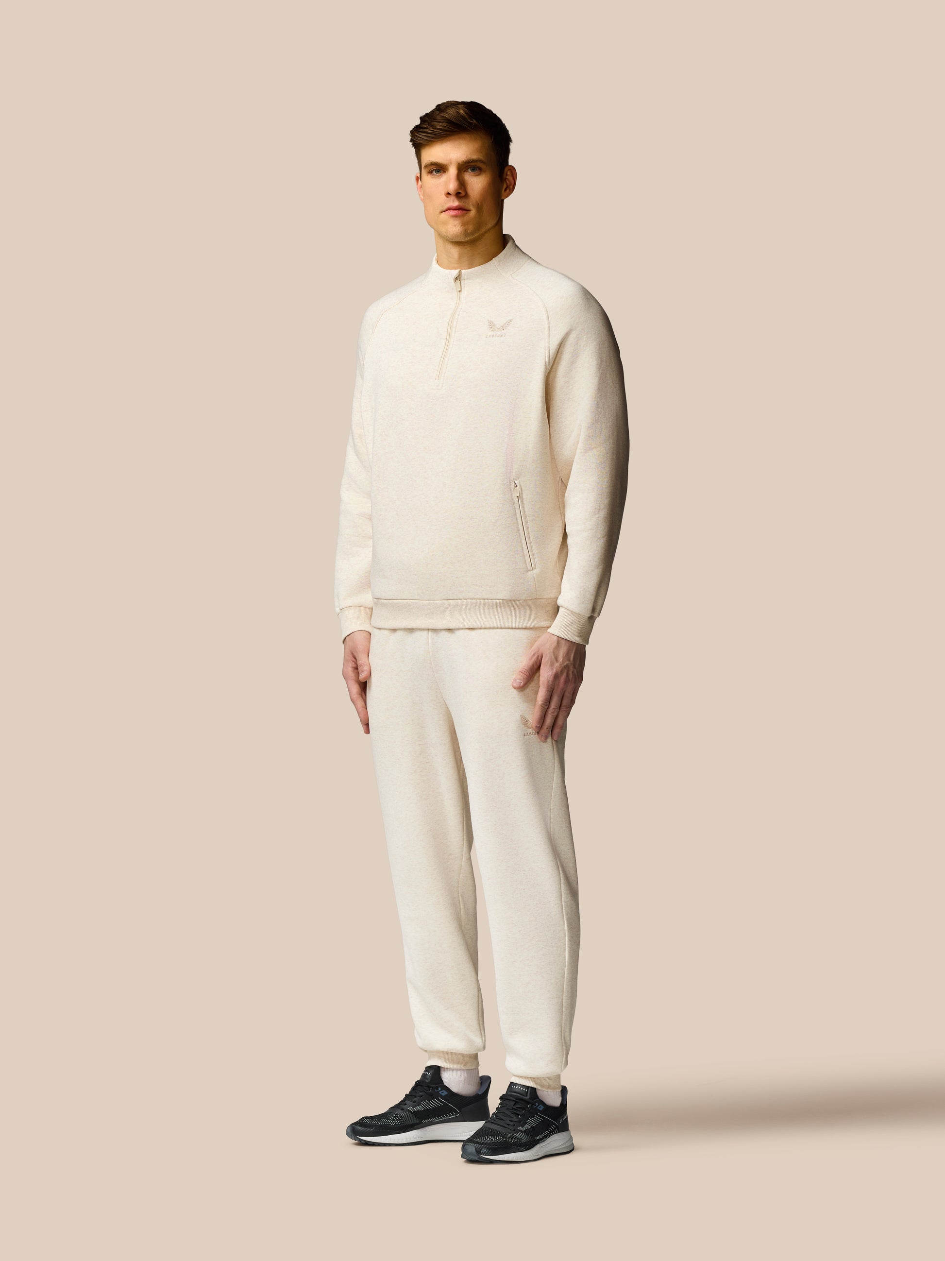 Man wearing a cream tracksuit against a beige background