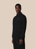 Man wearing a black half-zip sweatshirt on a beige background