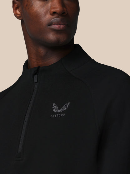 Person wearing a black jacket with a brand logo on a beige background