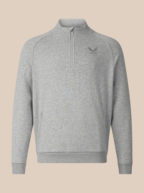 A light gray heathered quarter-zip sweatshirt with a small dark gray embroidered logo on the left chest, displayed on a solid beige background.
