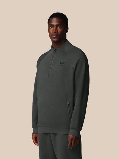 Man wearing a dark gray pullover with a small logo on a beige background