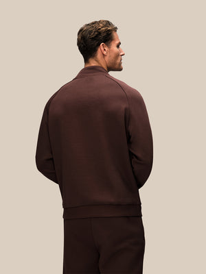 Back view of a man wearing a brown Adapt cotton fleece quarter zip sweatshirt.