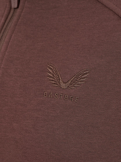 Close-up of a ribbed knit garment in a muted mauve-brown color, featuring an embossed winged logo and the word CASTORE on the chest.