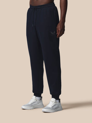 Person wearing black sweatpants and white sneakers on a beige background