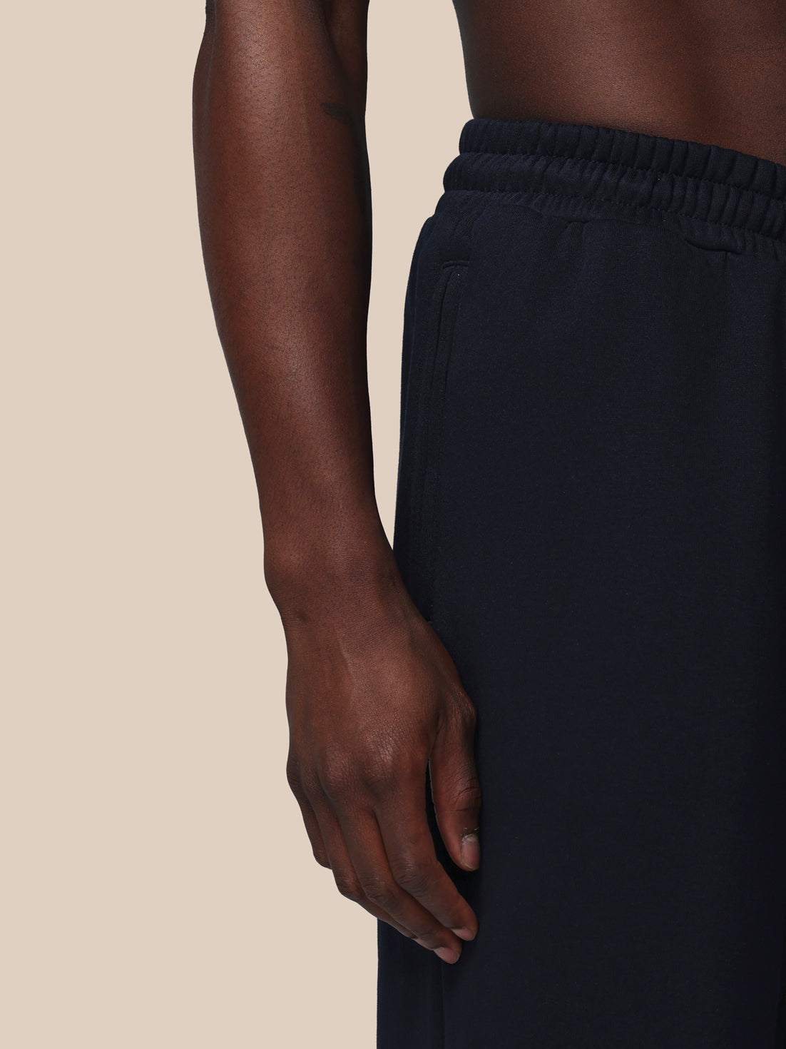 Person wearing black pants on a beige background
