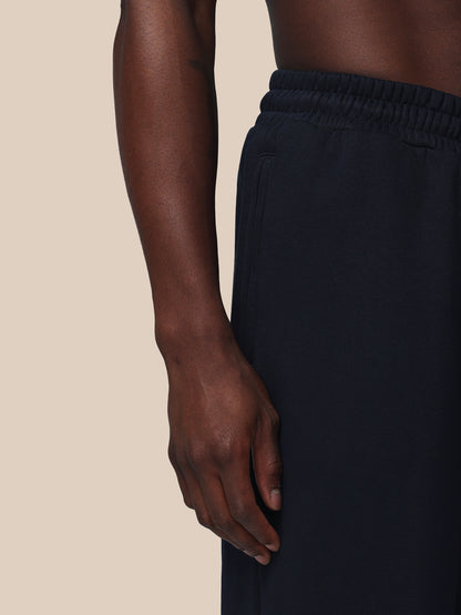 Person wearing black pants on a beige background