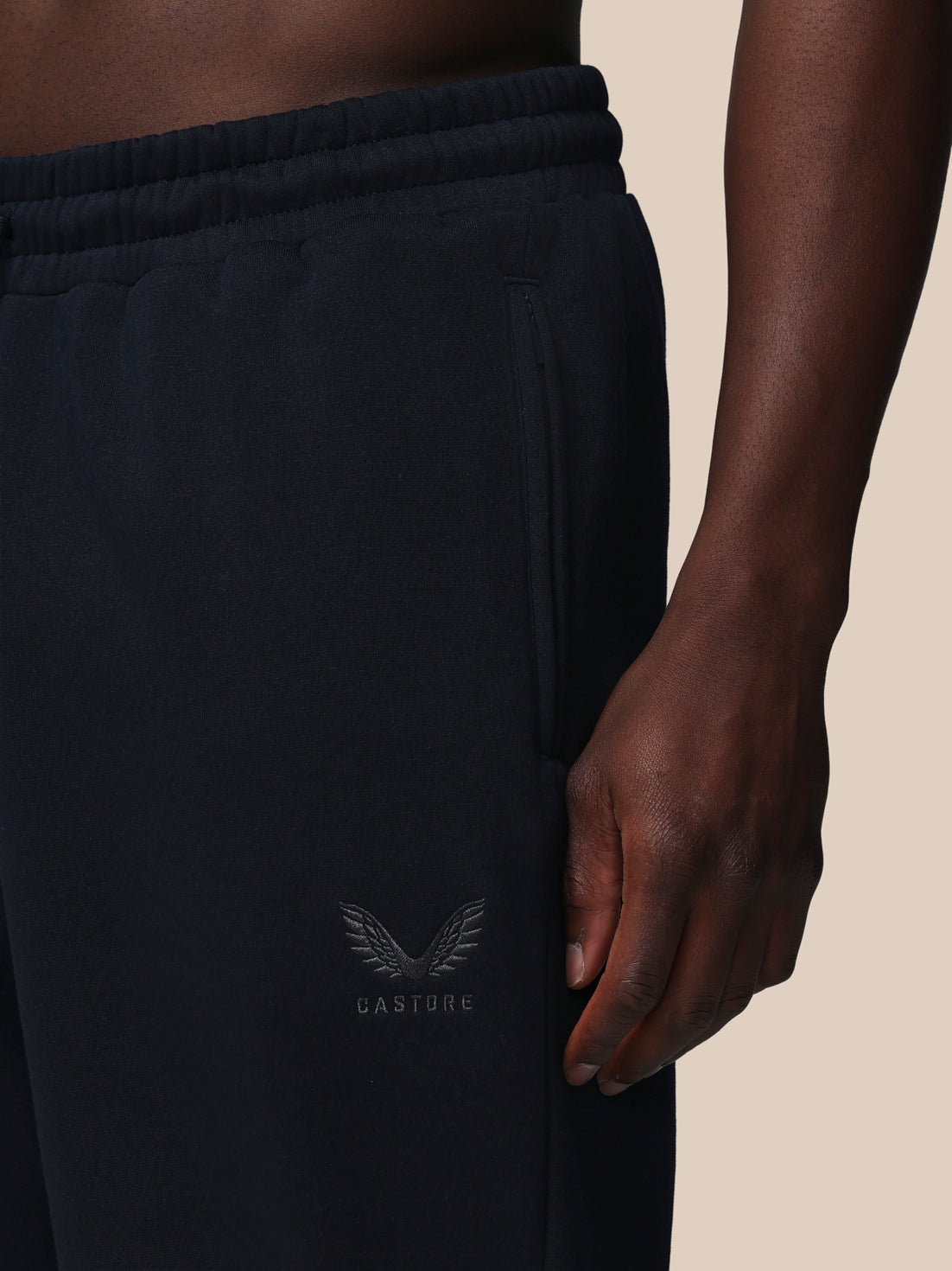 Black jogger pants with a brand logo on a beige background