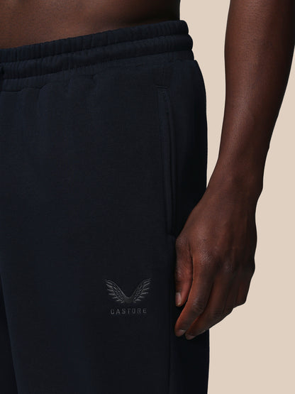 Black jogger pants with a brand logo on a beige background