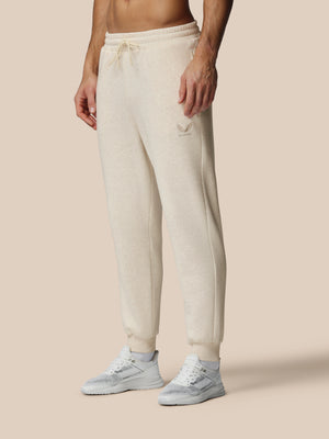 Person wearing beige sweatpants and white sneakers on a beige background
