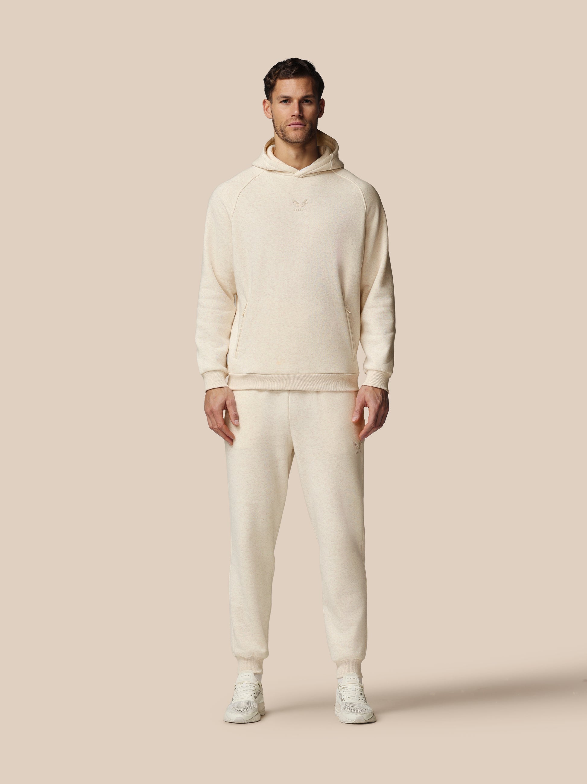 Man wearing a cream-colored hoodie and pants on a beige background