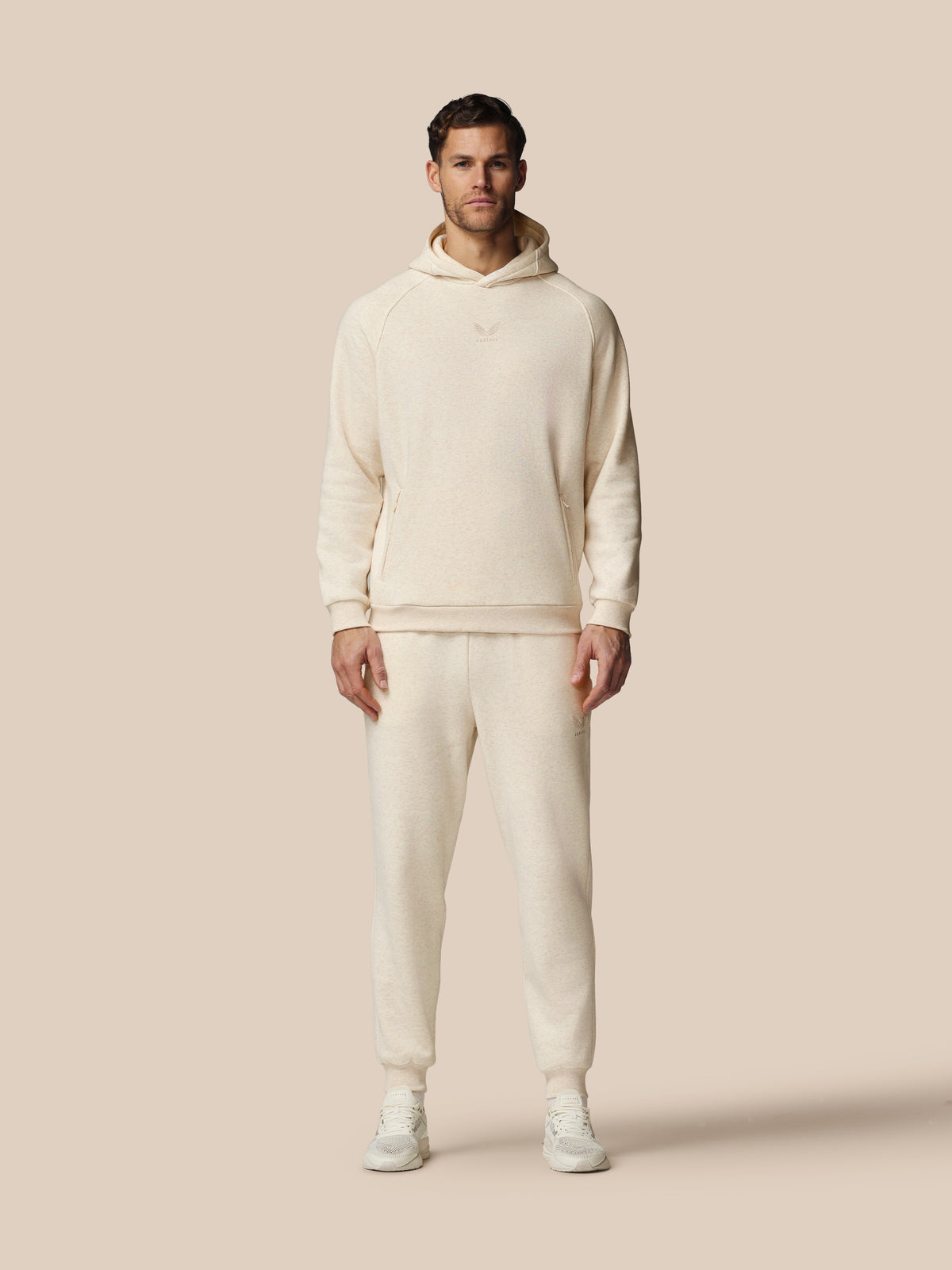 Man wearing a cream-colored hoodie and pants on a beige background